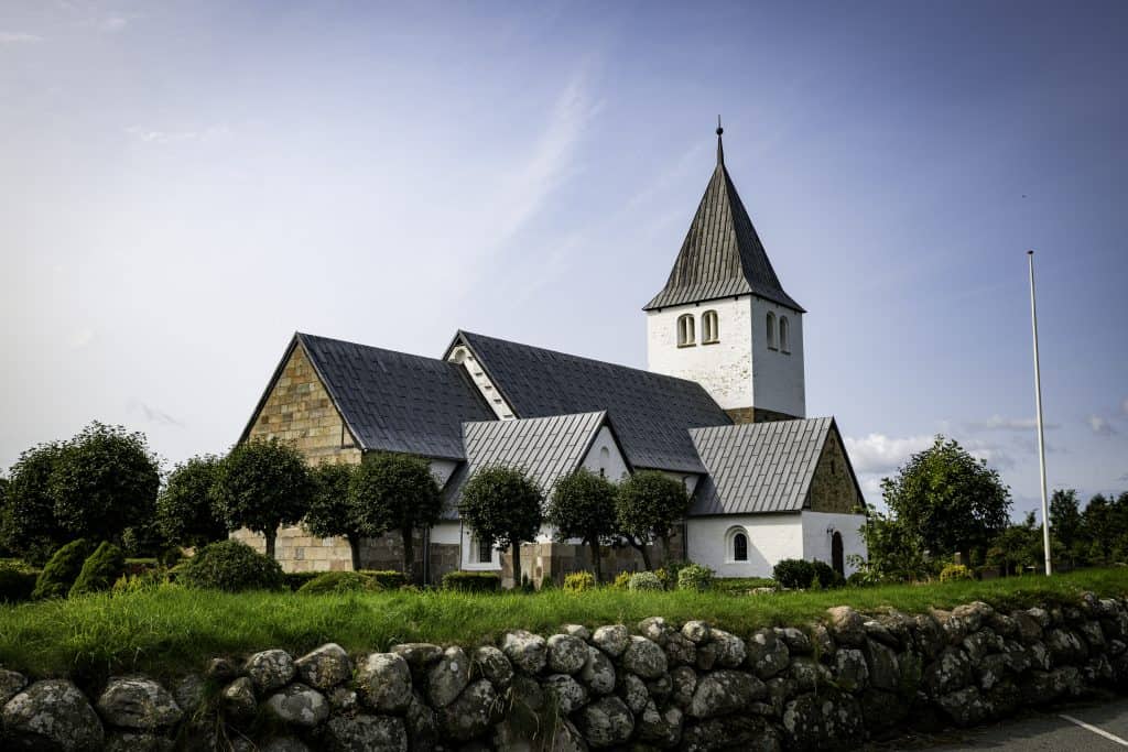 Exterior of a traditional church building with steeple and stained-glass windows, symbolizing historic worship and continuity of faith.